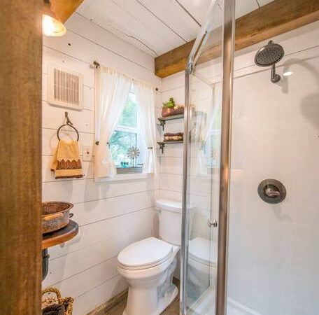 A closer look at the bathroom, which has a corner shower, good size toilet and rug on the floor.