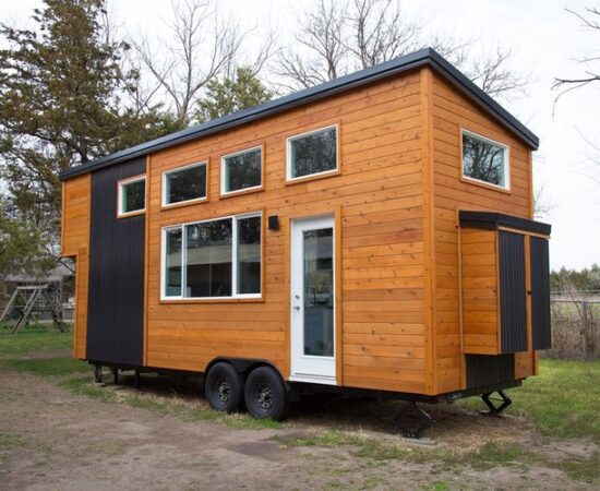 External view of the front of the tiny home in wheels, with 6 windows and front door.