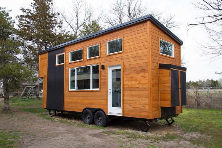 External view of the front of the tiny home in wheels, with 6 windows and front door.