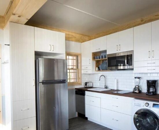 Woodland (in Nashville) tiny house's kitchen area, showing ample storage and a full size fridge/freezer and washer/dryer.